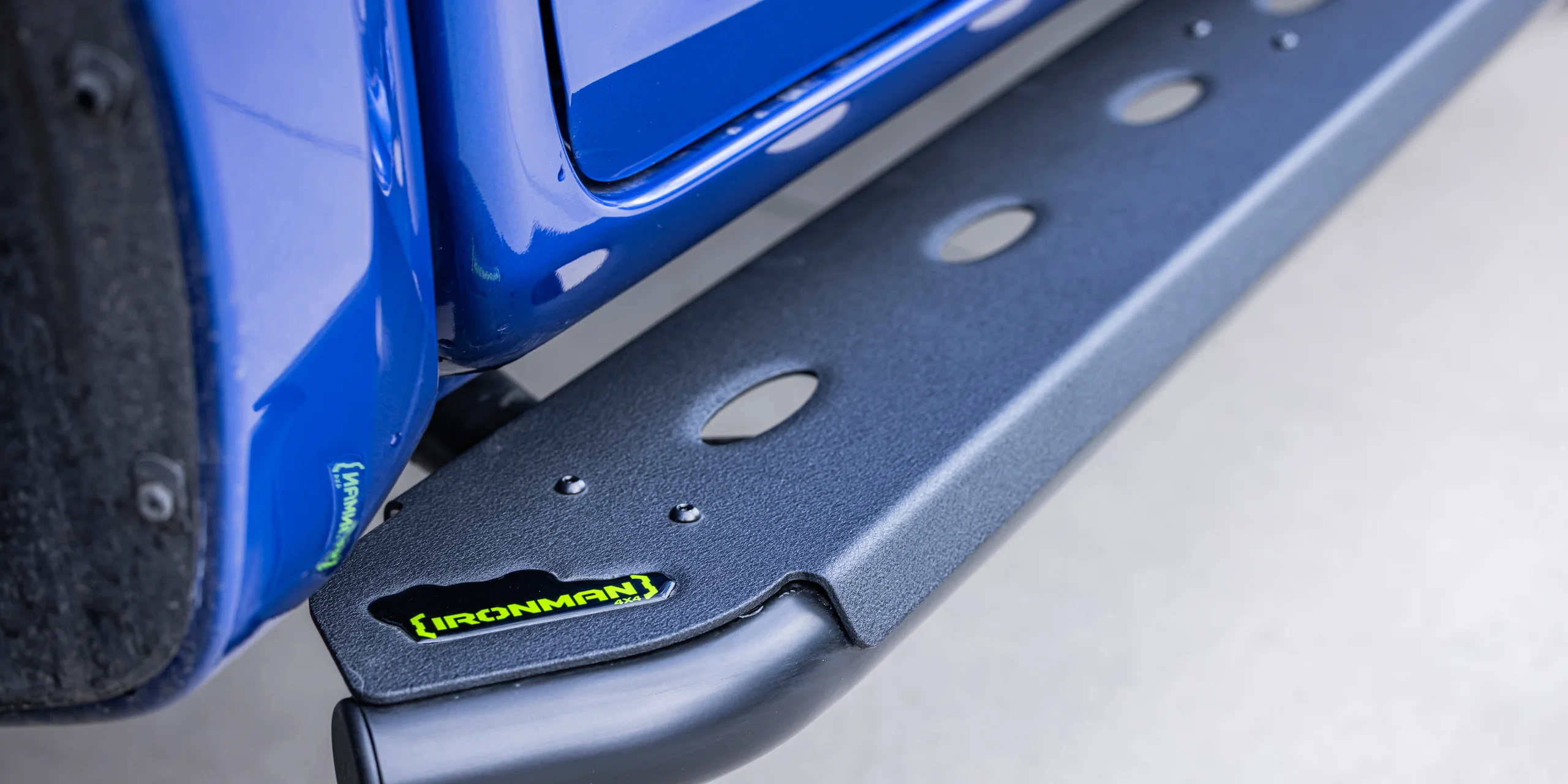 An IRONMAN 4X4 side step fitted along the sill of a blue dual cab ute