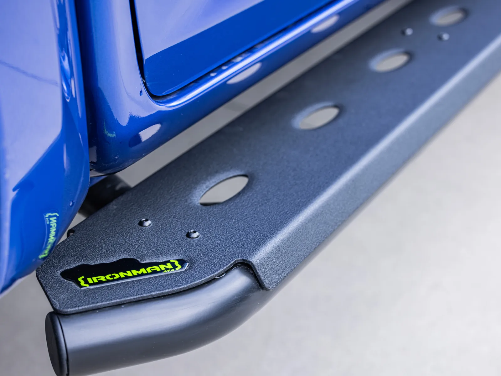 A side step with an IRONMAN 4X4 badge fitted along the sill of a blue dual cab ute