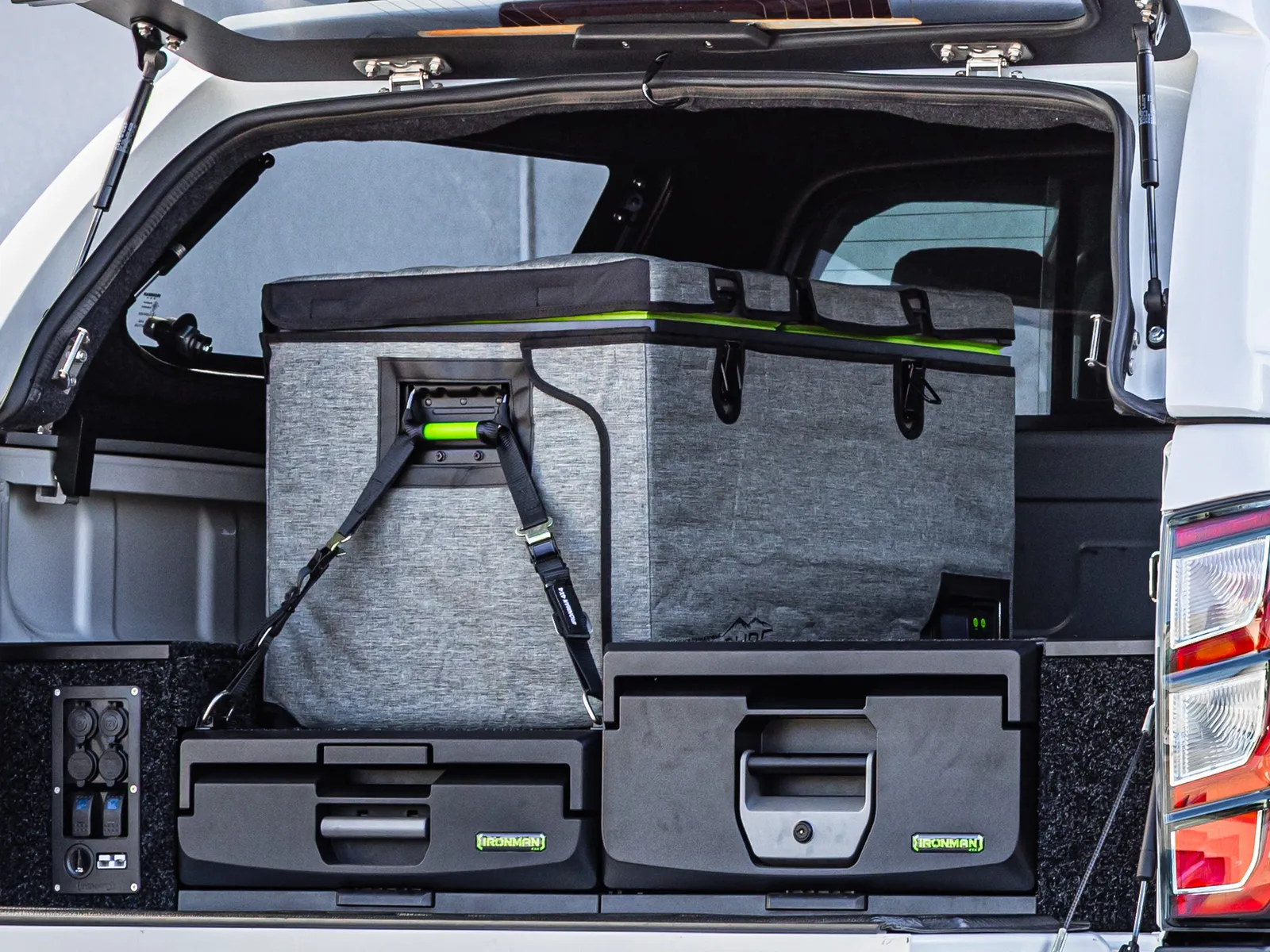 An open ute canopy with an IRONMAN 4X4 drawer system, a strapped fridge and a 12V outlet panel inside the tub