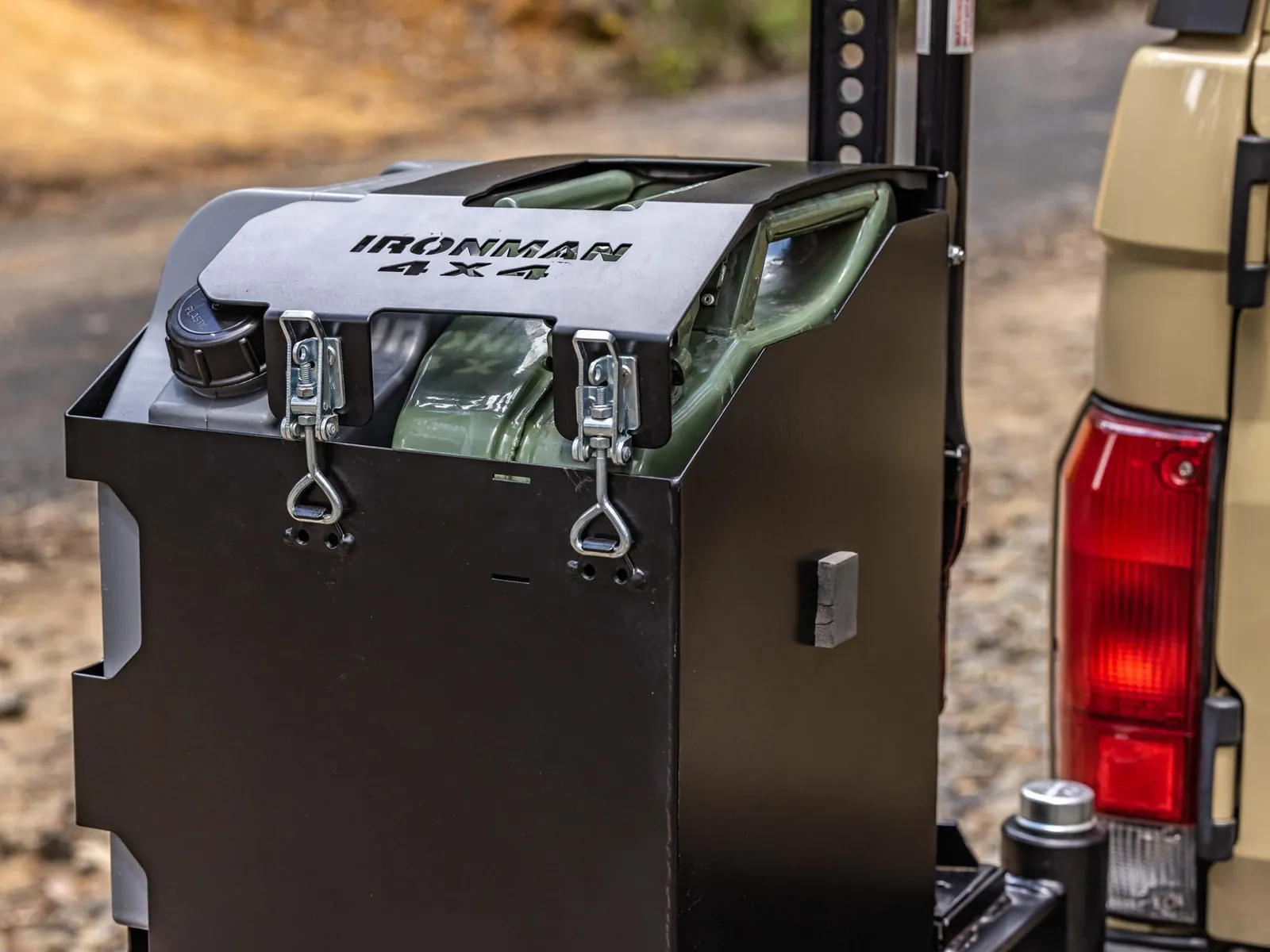 An IRONMAN 4X4 jerry can carrier with two jerry cans, mounted on the rear bar swing arm of a four wheel drive